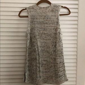 Thigh-length sleeveless sweater in neutral tones.